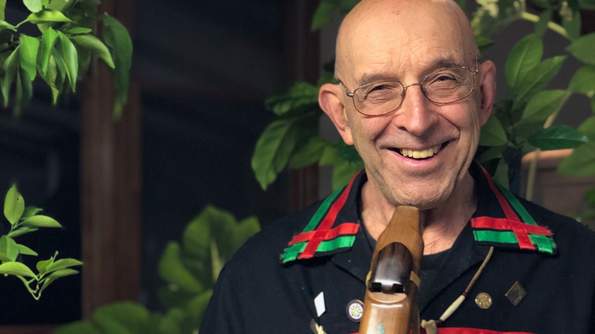 Man is black clothes with a wooden recorder in his hands. 