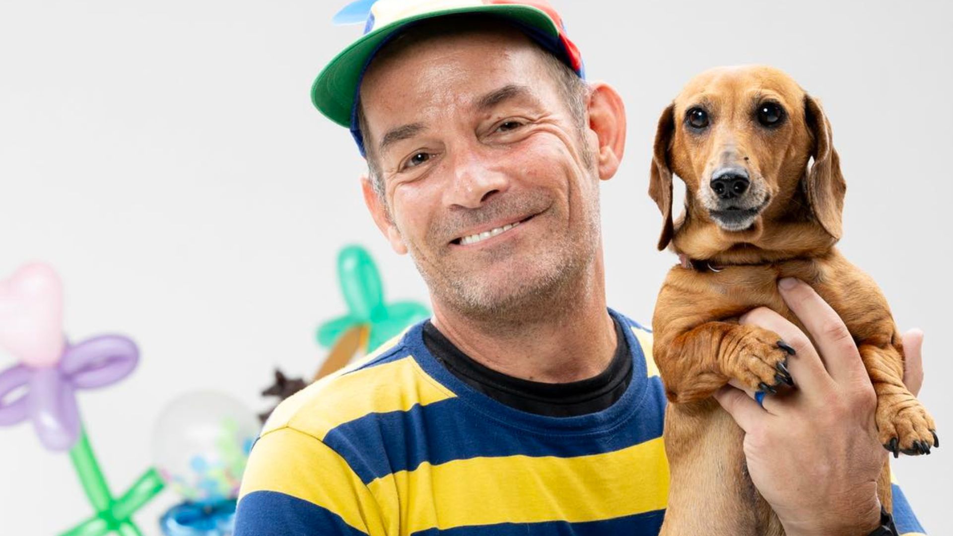 A man in a hat holding a dog.